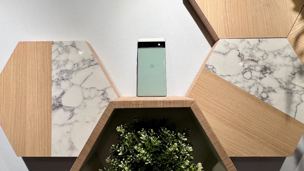 sage green google pixel 6a phone leaning on a wall mounted shelf