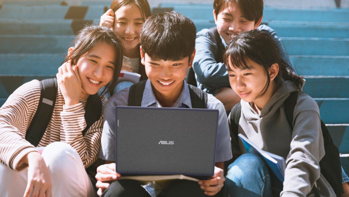 Happy,Young,Students,Looking,At,Laptop,And,Sitting,On,The