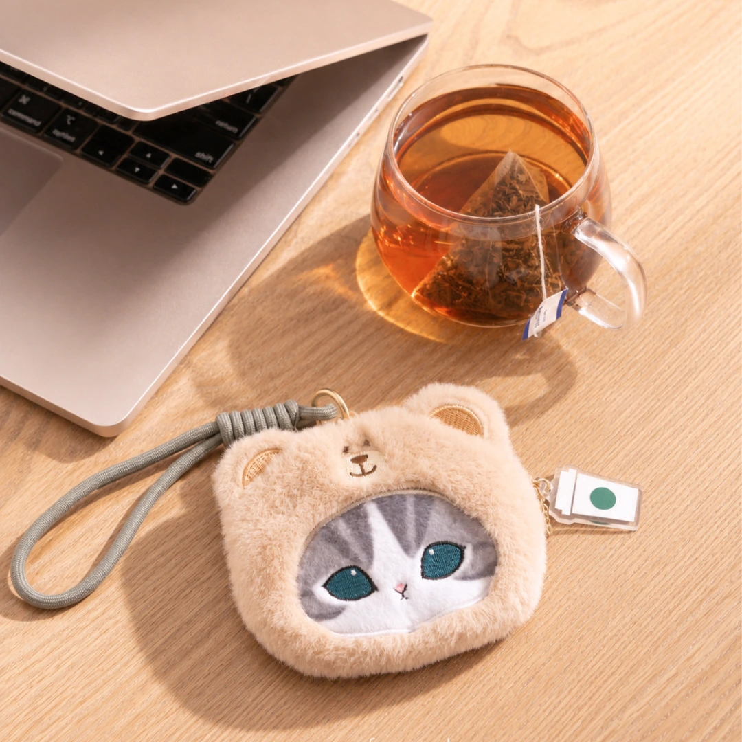 Mofusand + Starbucks Grey Cat wristlet next to a cup of tea and a macbook.